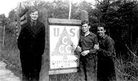 The main gate sign of
                  Camp Morgan, SP-4 in 1941. The three enrollees are
                  unidentified.