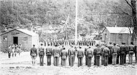 Retreat formation at Camp White showing a closer look at the field stone barracks foundations.